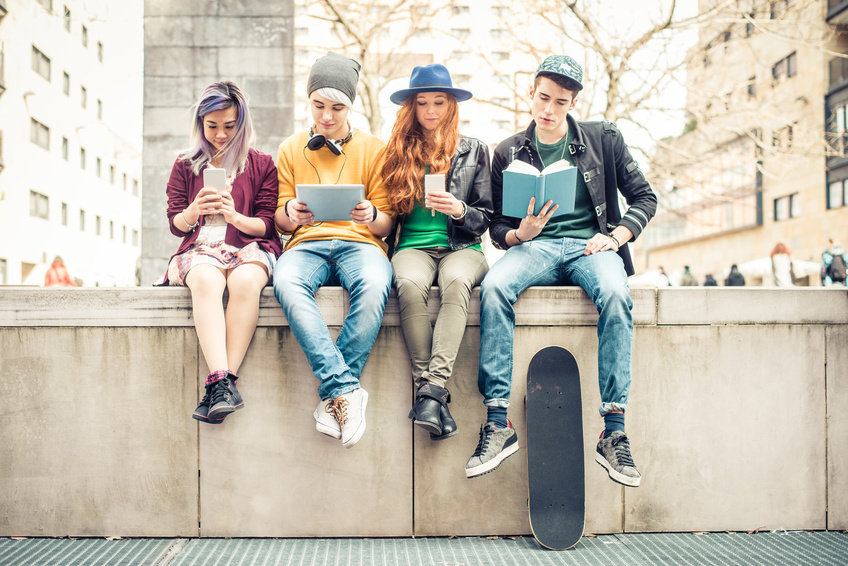 pubertät-fakten-blog vier teenager sitzen auf einer mauer und lesen